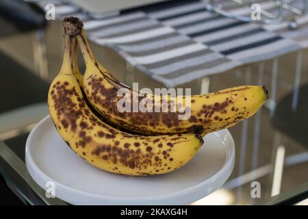 Vue rapprochée des bananes mûres placées sur une plaque blanche sur la table à manger Banque D'Images