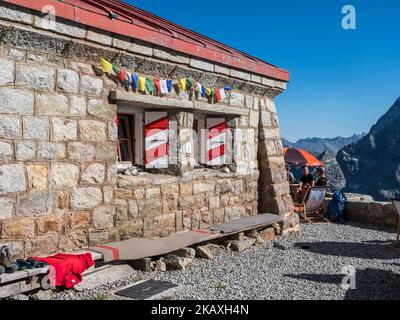 Refuge Cabane de l'UNE Neuve, touristes assis sur la terrasse, massif de l'aiguille rouges du Dolent à l'arrière, près de la Fouly, Val de Ferret, Suisse Banque D'Images