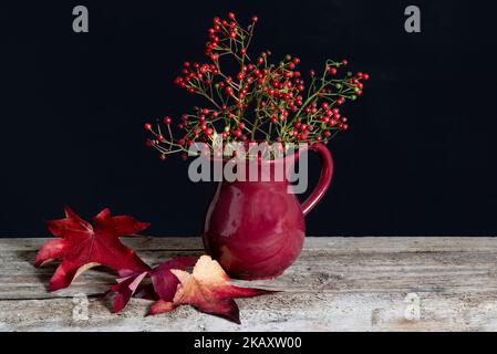 Bouquet de baies rouges sur la table dans un vase rouge. Banque D'Images