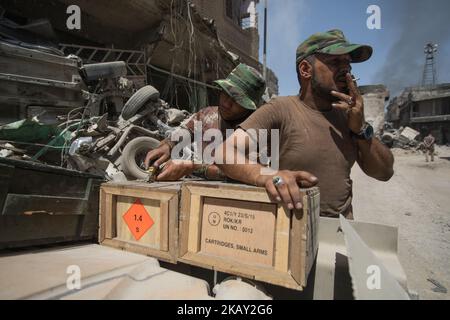 (7/11/2017) deux soldats ouvrent des boîtes de munitions à l'avant de Mossoul/Irak, tandis que de la fumée s'élève derrière eux (photo de Sebastian Backhaus/NurPhoto) Banque D'Images