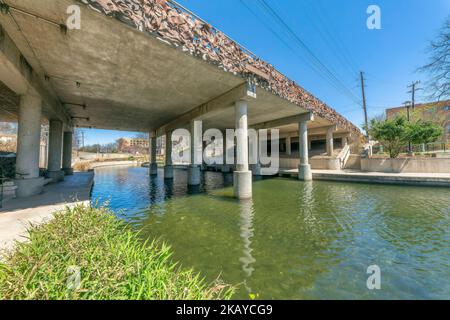 Vue sur un pont avec barrières métalliques et piliers en béton sur la petite rivière à San Antonio, Texas. Il y a un escalier à côté du pont de l'autre côté d'un Banque D'Images