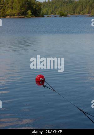 Bouy rouge utilisé pour amarrer de petits bateaux dans un lac. Banque D'Images