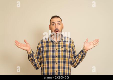 Génial. Beau portrait d'homme mi-longueur sur fond beige studio. Émotif surpris homme barbu debout avec la bouche ouverte. Émotions humaines Banque D'Images