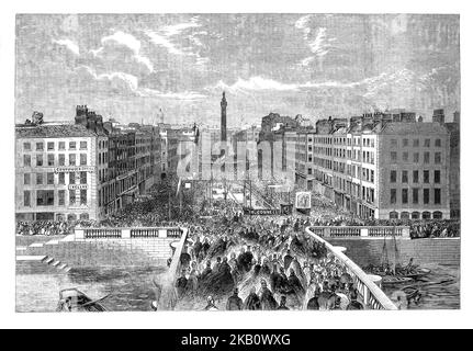 La foule observe la pose de la pierre de fondation du monument O'Connell à Sackville Street, aujourd'hui appelée O'Connell Street, Dublin, Irlande. Daniel O'Connell, alias « le Libérateur », a adopté la loi sur l'émancipation catholique en 1829 et a été élu Lord Mayor de Dublin. Plus loin, on peut voir la colonne de Nelson, épatée par l'IRA en 1966. Banque D'Images