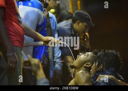 La jeunesse népalaise se livre à boire de la bière de riz sainte verse de la bouche l'énorme masque de l'idole Swet Bharab pendant le festival Indra Jatra célébré à la place Basantapur Durbar, Katmandou, Népal lundi, 24 septembre 2018. Les dévotés ont célébré le dieu de la pluie 'Indra' pendant 8 jours à Katmandou. (Photo de Narayan Maharajan/NurPhoto) Banque D'Images