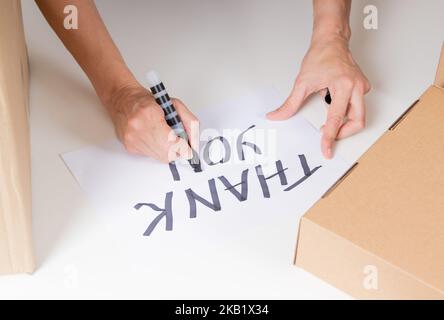 Femme main avec écriture de marqueur noir Merci sur le papier blanc. Don, organisme de bienfaisance, bénévolat, banque alimentaire, merci pour le concept des dons Banque D'Images