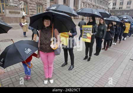 Les Ukrainiens portent des affiches et des parapluies noirs lors de leur marche silencieuse contre la traite des êtres humains appelée «Marche pour la liberté», dans le centre-ville de Kiev, en Ukraine, le 20 octobre 2018. La marche consacrée à la Journée européenne de lutte contre la traite, qui a eu lieu le 18 octobre, visait à sensibiliser le public au problème de la traite des êtres humains et de l'esclavage. (Photo par STR/NurPhoto) Banque D'Images