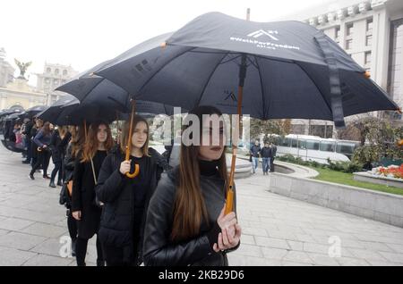 Les Ukrainiens portent des affiches et des parapluies noirs lors de leur marche silencieuse contre la traite des êtres humains appelée «Marche pour la liberté», dans le centre-ville de Kiev, en Ukraine, le 20 octobre 2018. La marche consacrée à la Journée européenne de lutte contre la traite, qui a eu lieu le 18 octobre, visait à sensibiliser le public au problème de la traite des êtres humains et de l'esclavage. (Photo par STR/NurPhoto) Banque D'Images