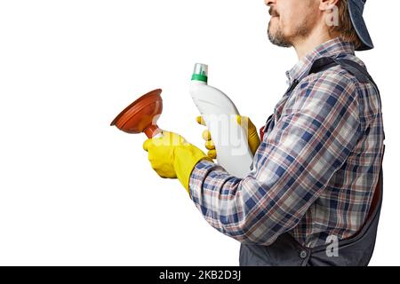 Un homme caucasien avec une moustache et une barbe en combinaison tient un piston et une bouteille de nettoyant pour tuyaux dans ses mains. Plombier gai sur fond gris Banque D'Images