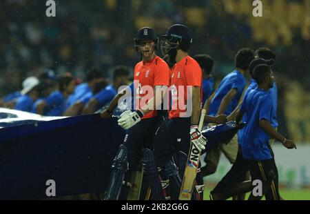 Les joueurs de cricket de l'Angleterre Moeen Ali et Ben Stokes reviennent dans le pavillon tandis que les couvertures de pluie arrivent au sol sous la pluie lors du seul match international de cricket de vingt-20 entre le Sri Lanka et l'Angleterre au stade international de cricket R Premadasa au Sri Lanka. Samedi 27 octobre 2018 (photo de Thharaka Basnayaka/NurPhoto) Banque D'Images