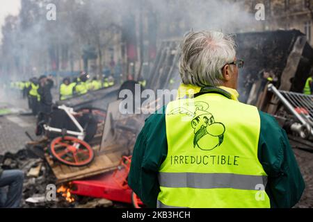 Paris, France, 24 novembre 2018. Les manifestants se tiennent devant un feu de meubles lors d'une manifestation contre les gilets jaunes (Gilets jaunes) contre la hausse des prix du pétrole et des coûts de la vie près de l'Arc de Triomphe sur les champs-Élysées. Les forces de sécurité à Paris ont tiré du gaz lacrymogène et du canon à eau pour disperser les manifestants. (Photo par Emeric Fohlen/NurPhoto) Banque D'Images