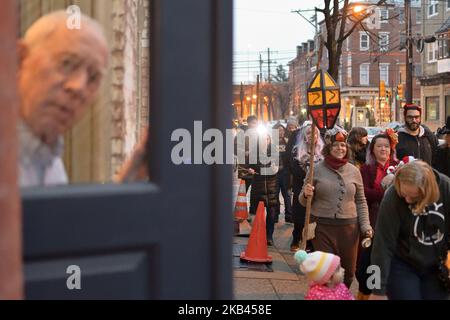 Un homme regarde à travers les galettes d'une porte d'entrée tandis que des centaines participent à la parade annuelle de huit Spirits Krampus Parade à travers le quartier des libertés du Nord de Philadelphie, PA sur 15 décembre 2018. Krampus est issu des traditions européennes comme le controversé Zwarte Piet (Black Pete) des pays-Bas et des personnages similaires qui, dans le folklore de différentes cultures européennes, s'en prennent à des enfants mal élevés. (Photo de Bastiaan Slabbers/NurPhoto) Banque D'Images