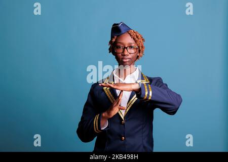 Une femme de bord afro-américaine fait un geste de temporisation avec les mains en T, exprimant le besoin de se reposer du travail. Femme sérieuse annonçant le symbole de pause avec les paumes, prise de vue en studio. Banque D'Images