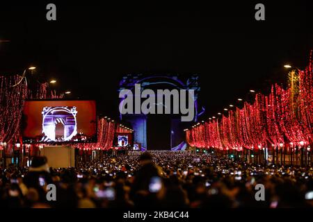 Les gens se rassemblent près de l'Arc de Triomphe illuminé sur les champs-Élysées pour les célébrations du nouvel an dans la capitale française, Paris, sur 31 décembre 2018. Un feu d'artifice et un spectacle son et lumière sous le thème 'Fraternité' sont prévus pour Vas-y sur les champs-Elysées malgré les plans pour d'autres manifestations anti-gouvernementales 'Yellow Vests' sur la célèbre avenue. (Photo par Sameer Al-Doumy/NurPhoto) Banque D'Images