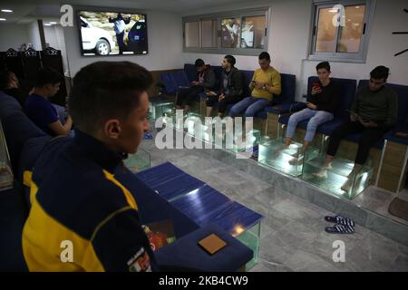 Les Palestiniens trempent leurs pieds dans un réservoir rempli de poissons dans un café de la ville de Gaza, en Palestine, sur 3 janvier 2019. Le chauffeur de café de Gaza a déclaré que son entreprise était en plein essor après le lancement du service de pédicure pour poissons dans la bande de Gaza assiégée. Une session de 30 minutes coûte environ $8 -- une somme énorme dans l'enclave côtière appauvrie. Mais des dizaines de personnes sont prêtes à payer le prix d'une fuite temporaire des conditions de vie difficiles à Gaza. (Photo de Majdi Fathi/NurPhoto) Banque D'Images