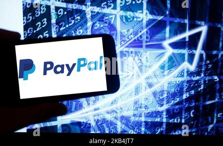 Le logo de PayPal est visible sur un écran de smartphone à côté d'un écran avec une illustration de la bourse. PayPal est répertorié dans Nasdaq. Le Nasdaq est la deuxième plus grande bourse au monde après la Bourse de New York. (Photo par Alexander Pohl/NurPhoto) Banque D'Images