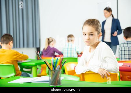 Bouleverser une écolière assise à un bureau dans une école primaire de classe Banque D'Images