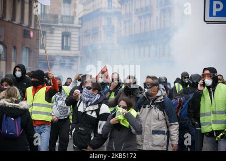 Les manifestants s'éloignent des nuages de gaz lacrymogène. Pour l'Acte XI du mouvement de la Vest jaune, plus de 10 000 personnes sont descendues dans les rues de Toulouse pour la manifestation antigouvernementale. Des accrochages ont eu lieu entre les manifestants et la police anti-émeute pendant 3 heures. La police anti-émeute a utilisé une cartouche de gaz lacrymogène et un canon à eau de police. Le mouvement des jaquettes jaunes a commencé sur 17 novembre par une protestation contre la hausse des taxes sur les produits pétroliers. La hausse des impôts a été le détonateur de leur colère contre le président français Macron et son gouvernement et leur demande de démission.Toulouse. France. 26 janvier 20 Banque D'Images