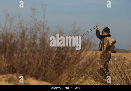 Un manifestant palestinien lance une pierre vers les forces israéliennes lors d'affrontements le long de la frontière avec la bande de Gaza, sur 29 janvier 2019. - Depuis près d'un an, les Palestiniens se sont rassemblés au moins une fois par semaine dans divers endroits le long de la frontière de Gaza pour des manifestations souvent violentes. Ils veulent pouvoir rentrer dans les foyers dont leurs familles ont fui lors de la guerre entourant la création d'Israël en 1948, ainsi que la fin du blocus de Gaza par l'État juif. (Photo de Majdi Fathi/NurPhoto) Banque D'Images