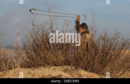 Un manifestant palestinien lance une pierre vers les forces israéliennes lors d'affrontements le long de la frontière avec la bande de Gaza, sur 29 janvier 2019. - Depuis près d'un an, les Palestiniens se sont rassemblés au moins une fois par semaine dans divers endroits le long de la frontière de Gaza pour des manifestations souvent violentes. Ils veulent pouvoir rentrer dans les foyers dont leurs familles ont fui lors de la guerre entourant la création d'Israël en 1948, ainsi que la fin du blocus de Gaza par l'État juif. (Photo de Majdi Fathi/NurPhoto) Banque D'Images