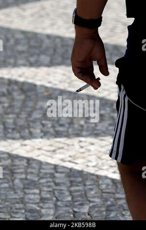 Un fumeur tient une cigarette à Lisbonne, au Portugal, sur 4 septembre 2019. La loi approuvant les mesures pour la collecte et le traitement des déchets de tabac et punit avec des amendes entre 25 et 250 euros ceux qui jettent des boires sur la voie publique a été publiée sur le Journal de 3 septembre en République. Les mégots de cigarettes, les cigares ou autres cigarettes contenant des produits du tabac seront assimilés, à partir d'aujourd'hui, aux déchets urbains solides, et leur élimination dans l'espace public est donc interdite. (Photo par Pedro Fiúza/NurPhoto) Banque D'Images