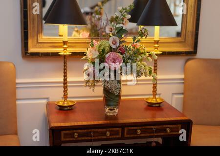 Bouquet de fleurs sur une table avec deux lampes ombrées devant le miroir Banque D'Images