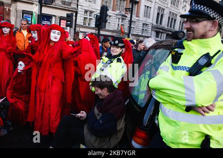 Un policier rit comme l'un des écologistes de la troupe d'art de la performance la Brigade rouge prend des gestes vers lui à Trafalgar Square tandis que les membres du groupe activiste du changement climatique extinction Rebellion (XR) prennent part au deuxième jour de la "rébellion internationale" du groupe à Londres, Angleterre, sur 8 octobre, 2019. En début de soirée mardi, la police métropolitaine a signalé qu'un total de 531 arrestations avaient eu lieu au cours des deux jours de manifestations dans la ville jusqu'à présent, avec des policiers qui travaillaient à nettoyer les personnes et les tentes de nombreux sites repris hier par des activistes. Similaire b Banque D'Images