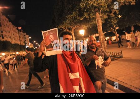 Un jeune homme portant le drapeau de la Tunisie lève l'affiche de Kais Saied lorsqu'il assiste à la célébration de la victoire de Kais Saied lors de l'élection présidentielle tunisienne après un scrutin de sortie, sur l'avenue Habib Bourguiba, dans la capitale Tunis, sur 13 octobre 2019. (Photo de Chedly Ben Ibrahim/NurPhoto) Banque D'Images