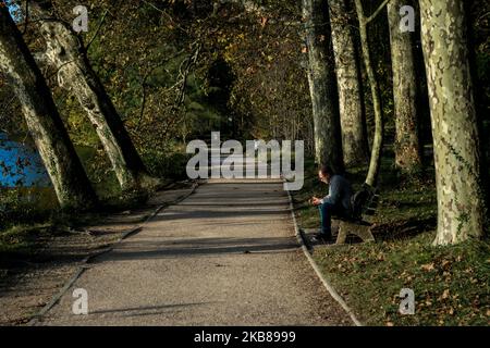 Un homme est assis sur un banc au lever du soleil au parc de la tête d'Or à Lyon, en France, sur 14 octobre 2019. (Photo de Nicolas Liponne/NurPhoto) Banque D'Images