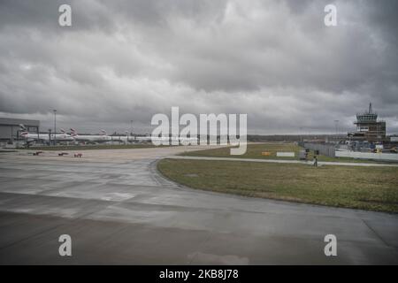 À l'aéroport de Gatwick, des avions ont garé des hangars à cargaison en arrière-plan avec une tour de contrôle de la circulation aérienne qui a couvert la nuit hivernale Banque D'Images