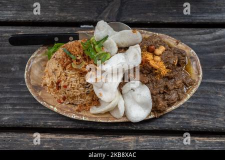 Renning Daging, ragoût de bœuf épicé indonésien, et riz frit épicé Nasi goreng, indonésien ou Bali sur une table en bois rugueuse. Banque D'Images