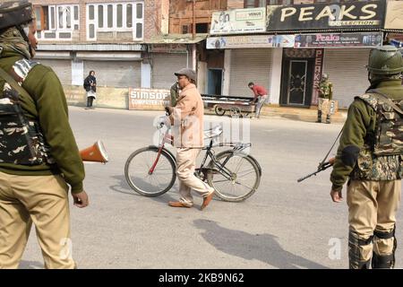 Un cachemiri passe son vélo alors que les forces paramilitaires indiennes se tiennent pendant les restrictions à Srinagar, dans le Cachemire administré par l'Inde, le 01 novembre 2019. Le gouvernement indien a rejeté les prières du vendredi dans HIstoric Jamia Masjid pour 13th fois. Toutefois, les autorités ont imposé des restrictions dans de nombreuses parties de la vallée, tandis que les services mobiles prépayés et les services Internet restent gonflés le 89th jour. (Photo de Muzamil Mattoo/NurPhoto) Banque D'Images