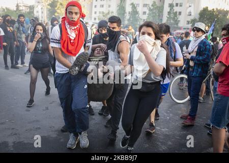 Les volontaires portent un manifestant anti-gouvernement affecté par des gaz lacrymogènes lancés par des policiers anti-émeutes des enfants lors d'une manifestation à Santiago, au Chili, au 31 octobre 2019. (Photo de Jerez Gonzalez/NurPhoto) Banque D'Images