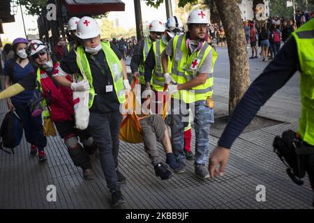 Les volontaires portent un manifestant anti-gouvernement affecté par des gaz lacrymogènes lancés par des policiers anti-émeutes des enfants lors d'une manifestation à Santiago, au Chili, au 31 octobre 2019. (Photo de Jerez Gonzalez/NurPhoto) Banque D'Images