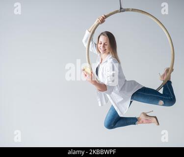 Gymnaste caucasien de sexe féminin faisant des exercices de canulars aériens et en utilisant un smartphone. Banque D'Images