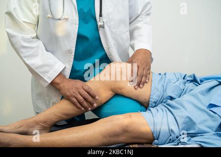 Médecin asiatique physiothérapeute examinant, massant et traitement genou et jambe d'un patient senior dans la clinique orthopédique infirmière hôpital. Banque D'Images