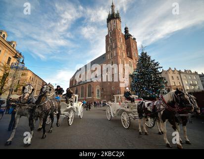 Vue sur les calèches en face de l'arbre de Noël principal, près de la basilique Sainte-Marie, sur la place du marché de Cracovie. Dimanche, 1 décembre 2019, à Cracovie, petite Pologne Voivodeship, Pologne. (Photo par Artur Widak/NurPhoto) Banque D'Images