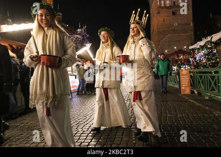 Les jeunes filles de Kalmar, Suède vêtues d'une robe blanche et d'une ceinture rouge (symbole du martyre) portent des bougies en procession le long de la foire de Noël de Gdansk dans la région du centre de la vieille ville sont vues à Gdansk, Pologne, le 2 décembre 2019 . L'un d'eux porte une couronne de bougies sur sa tête. Les filles vêtues de Sainte Lucy (Sankta Lucia) portent des biscuits en procession et chantent des chansons. Il est dit que célébrer avec vivile la Saint Lucy's Day aidera à vivre les longs jours d'hiver avec suffisamment de lumière. (Photo de Michal Fludra/NurPhoto) Banque D'Images