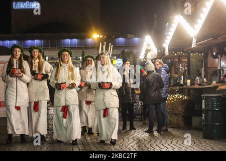 Les jeunes filles de Kalmar, Suède vêtues d'une robe blanche et d'une ceinture rouge (symbole du martyre) portent des bougies en procession le long de la foire de Noël de Gdansk dans la région du centre de la vieille ville sont vues à Gdansk, Pologne, le 2 décembre 2019 . L'un d'eux porte une couronne de bougies sur sa tête. Les filles vêtues de Sainte Lucy (Sankta Lucia) portent des biscuits en procession et chantent des chansons. Il est dit que célébrer avec vivile la Saint Lucy's Day aidera à vivre les longs jours d'hiver avec suffisamment de lumière. (Photo de Michal Fludra/NurPhoto) Banque D'Images