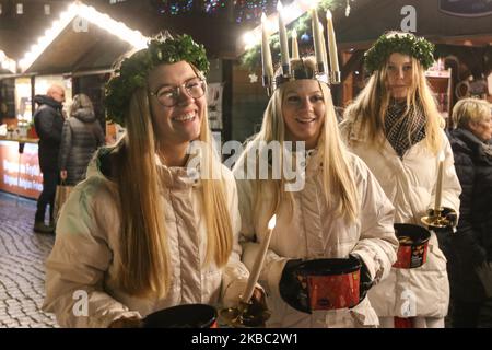 Les jeunes filles de Kalmar, Suède vêtues d'une robe blanche et d'une ceinture rouge (symbole du martyre) portent des bougies en procession le long de la foire de Noël de Gdansk dans la région du centre de la vieille ville sont vues à Gdansk, Pologne, le 2 décembre 2019 . L'un d'eux porte une couronne de bougies sur sa tête. Les filles vêtues de Sainte Lucy (Sankta Lucia) portent des biscuits en procession et chantent des chansons. Il est dit que célébrer avec vivile la Saint Lucy's Day aidera à vivre les longs jours d'hiver avec suffisamment de lumière. (Photo de Michal Fludra/NurPhoto) Banque D'Images