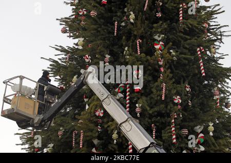 Un ouvrier décorera le principal arbre de Noël sur la place Sophia à Kiev, en Ukraine, le 05 décembre 2019. Le principal arbre de Noël ukrainien de 30 mètres de haut et pesant 100 tonnes, sera décoré avec 750 jouets de bonbons et 4 kilomètres de guirlandes. Les personnages du ballet « casse-noisette » et des contes de fées ukrainiens le plaineront. L'arbre de Noël sera éclairé le jour de Saint-Nicolas sur 19 décembre 2019. (Photo par STR/NurPhoto) Banque D'Images