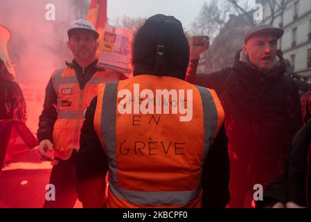 Plusieurs centaines de cheminots ont manifesté avec leur veste orange SNCF au milieu de la fumée rouge, dont un qui a écrit « Cheminots en grève » sur son dos le jeudi 12 décembre 2019, Le lendemain des annonces du premier ministre sur la réforme des pensions et le huitième jour de la grève contre la réforme, les syndicats ont demandé une troisième journée de manifestation pour démontrer leur refus. Quelques milliers de personnes ont répondu à l'appel, principalement des cheminots de la SNCF et de la RATP, des professeurs, des étudiants et des syndicalistes de la CGT. (Photo de Samuel Boivin/NurPhoto) Banque D'Images