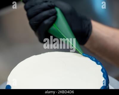 chef pâtissier concepteur de gâteaux préparant un cheesecake blanc bleu dans un laboratoire de cuisine Banque D'Images