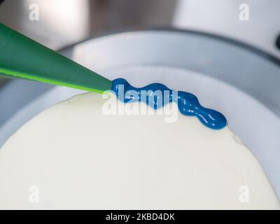chef pâtissier concepteur de gâteaux préparant un cheesecake blanc bleu dans un laboratoire de cuisine Banque D'Images