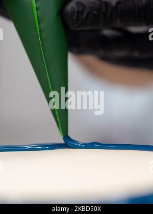 chef pâtissier concepteur de gâteaux préparant un cheesecake blanc bleu dans un laboratoire de cuisine Banque D'Images