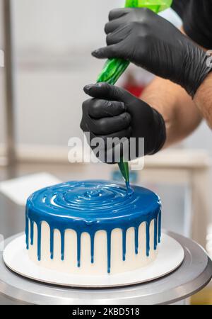 chef pâtissier concepteur de gâteaux préparant un cheesecake blanc bleu dans un laboratoire de cuisine Banque D'Images