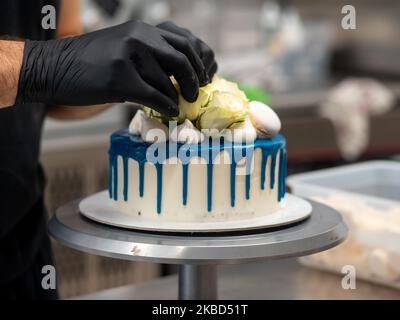 chef pâtissier concepteur de gâteaux préparant un cheesecake blanc bleu dans un laboratoire de cuisine Banque D'Images