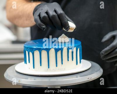 chef pâtissier concepteur de gâteaux préparant un cheesecake blanc bleu dans un laboratoire de cuisine Banque D'Images