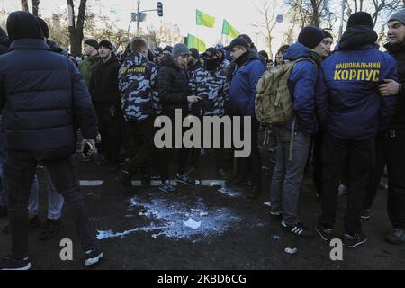 Les activistes des mouvements ukrainiens d'extrême droite se tiennent autour de la tache de lait sur le sol après avoir lavé le gaz lacrymogène hors de leur visage lors d'une protestation des ouvriers agricoles contre la réforme agraire à Kiev, Ukraine, 17 décembre 2019. Des dizaines de militants d'extrême-droite se sont opposés à la police devant le Parlement ukrainien alors que des manifestants protestaient pacifiquement contre une éventuelle loi sur le marché foncier adoptée par les législateurs de la Verkhovna Rada. En novembre 2019, le Parlement a adopté la première lecture d'un projet de loi du gouvernement sur la modification de certains actes législatifs de l'Ukraine concernant le renouvellement des terres agricoles, W Banque D'Images