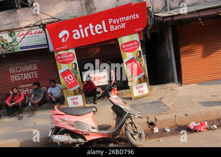 Les gens se reposent devant une boutique avec une annonce du géant indien des télécommunications Bharti Airtel à Mumbai, Inde, le 18 décembre 2019. (Photo par Himanshu Bhatt/NurPhoto) Banque D'Images